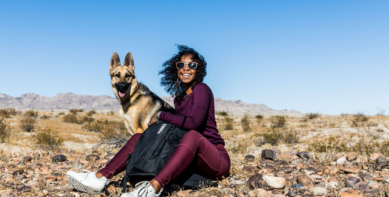 Woman sitting dog and smiling in a desert landscape