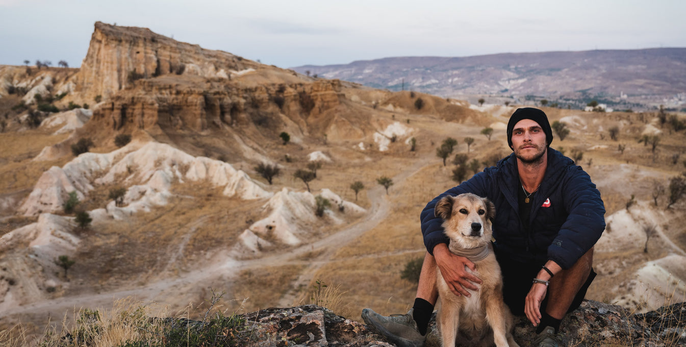Man and dog sitting in a desert landscape in Kyrgystan