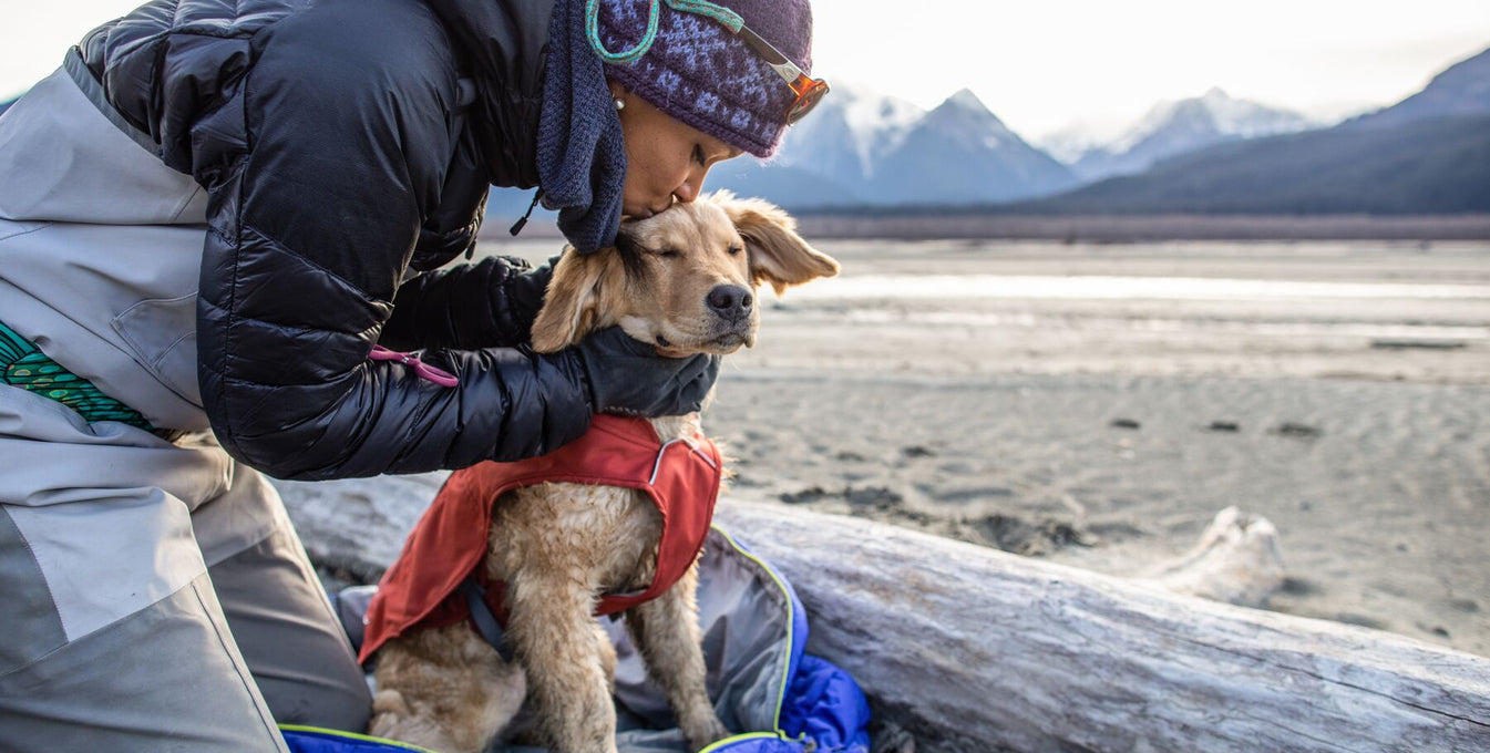 woman wearing fishing gear kissing dog on head