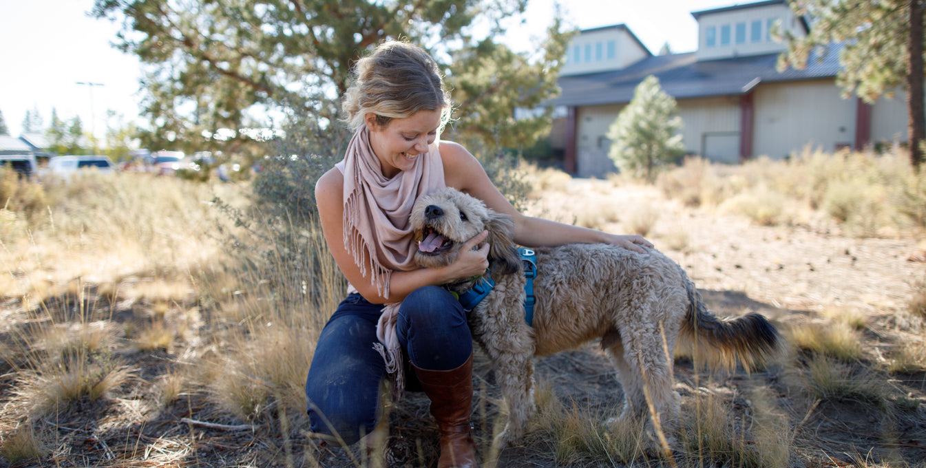 A woman and her dog hug and smile for the camera. 