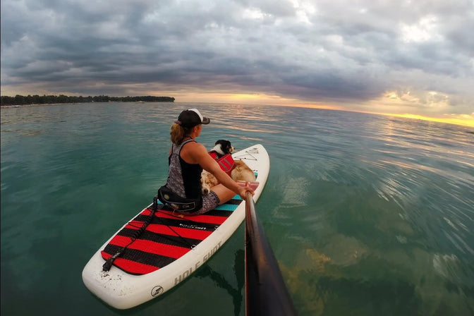 Maria on SUP with dogs in float coat dog life jackets on great lakes.